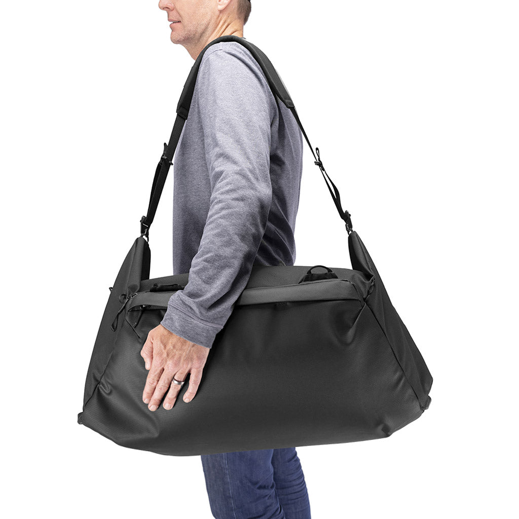 (image), carrying the 65L black duffel bag using its shoulder strap, BTRD-65-BK-1