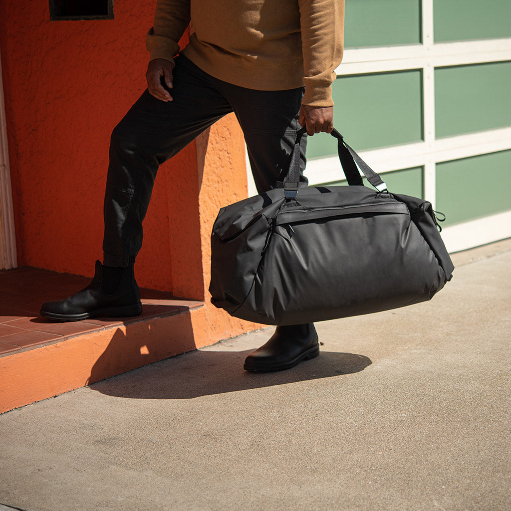 (image), carrying the 65L black duffel bag using its hand strap, BTRD-65-BK-1